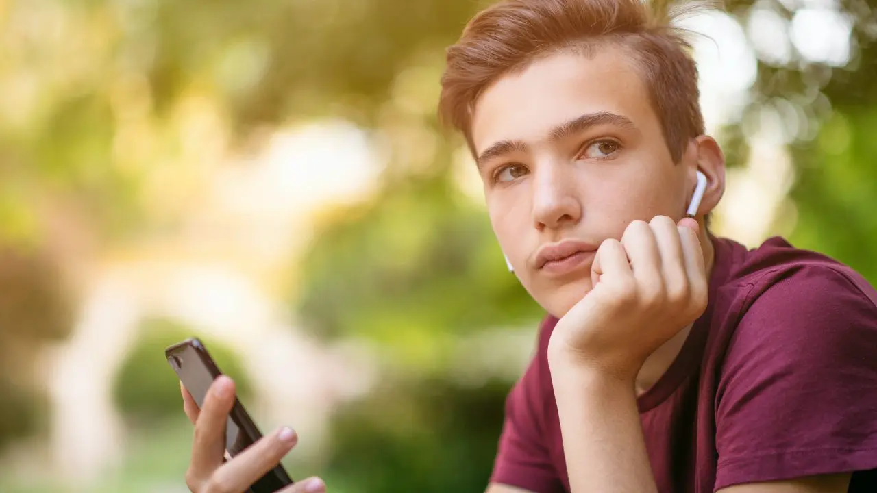 Teenage boy looking sad while listening to music