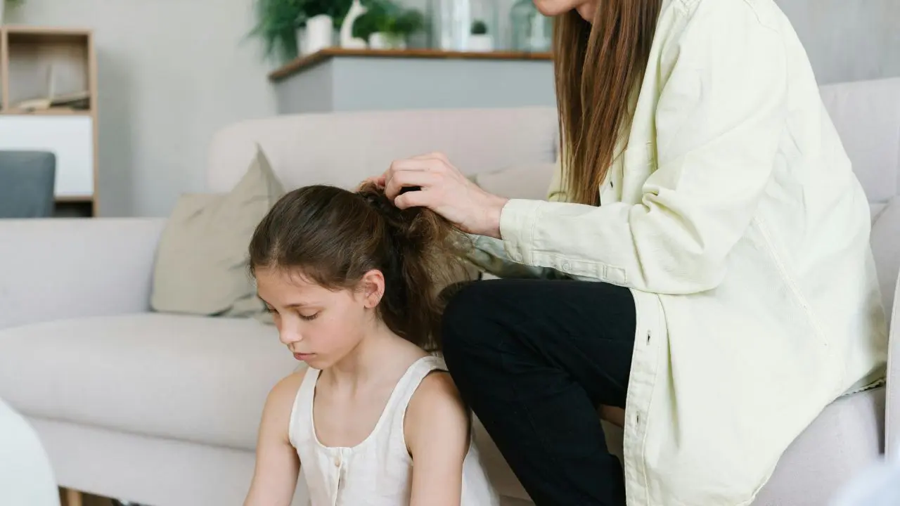 Small girl sat on the floor looking sad while her mum strokes her hair