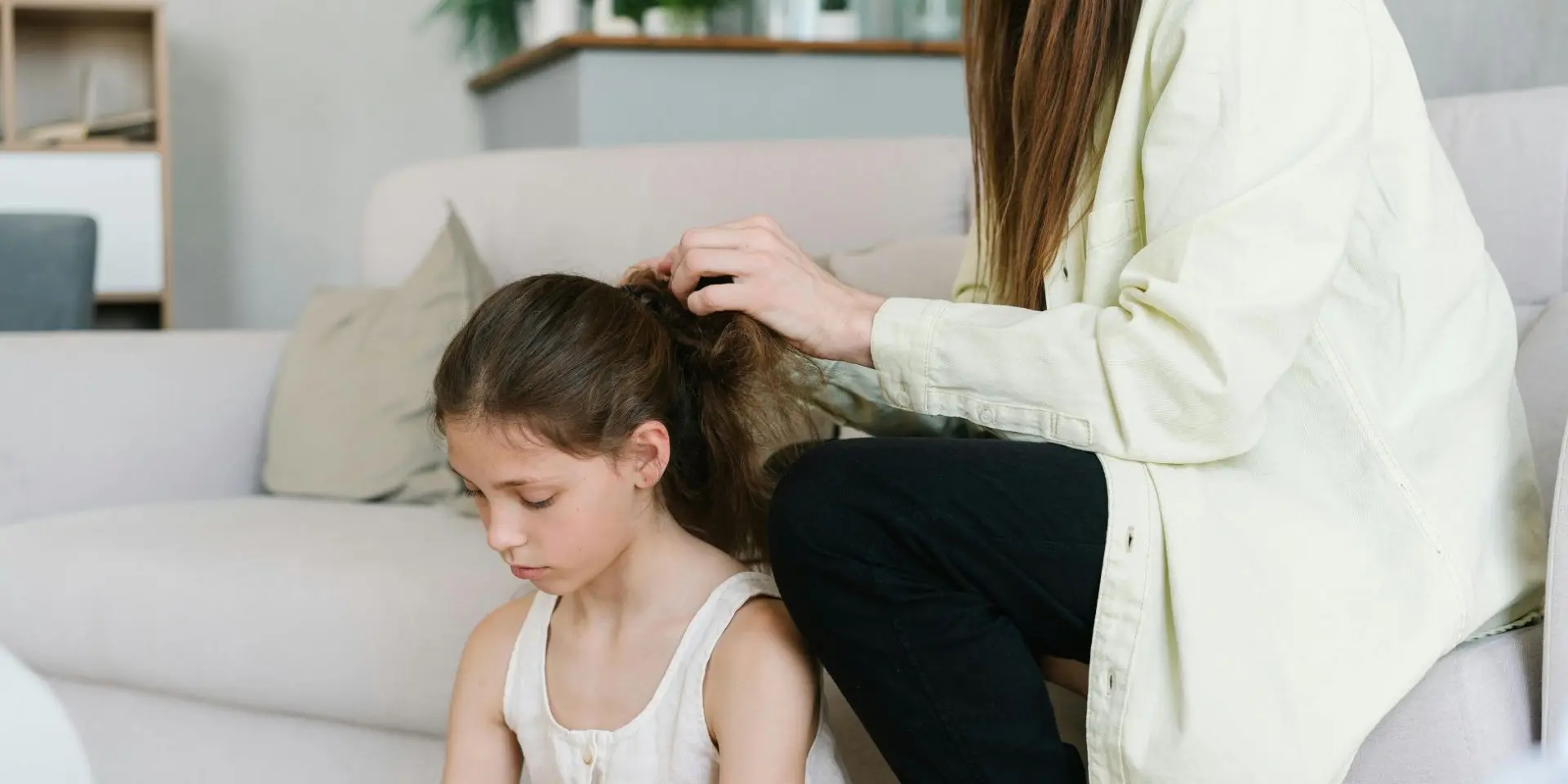 Small girl sat on the floor looking sad while her mum strokes her hair
