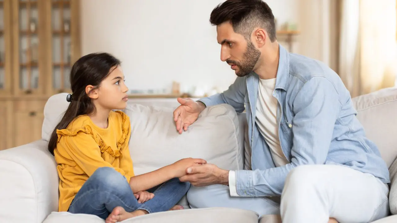 Man holding the hand of his daughter while they talk