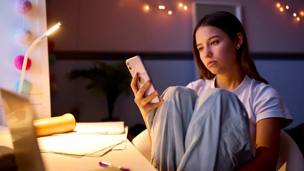 Teenage girl looking at her phone and looking sad