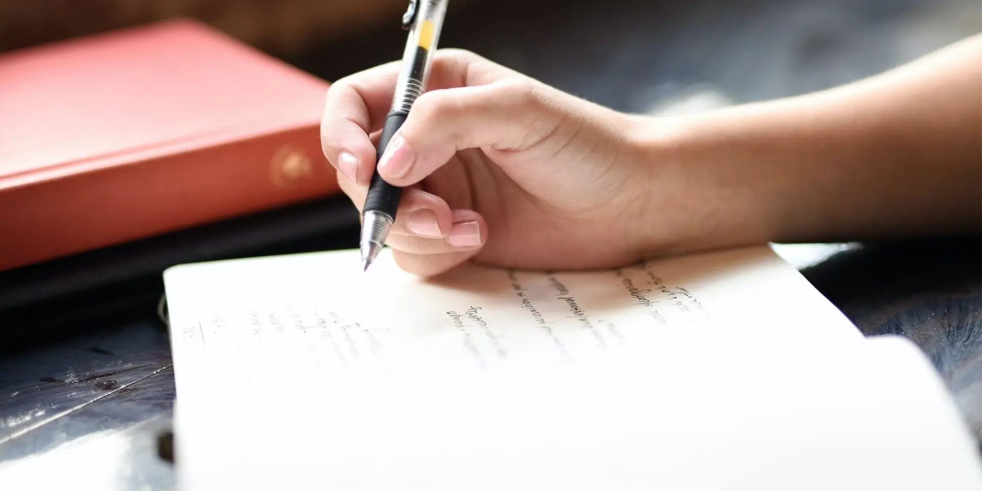 Open notepad with hand holding a pen and about to write