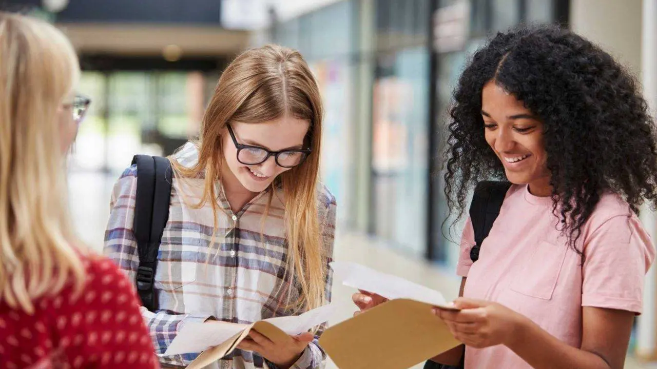 Three teenage girls reading their exam results - how can results day impact grieving young people