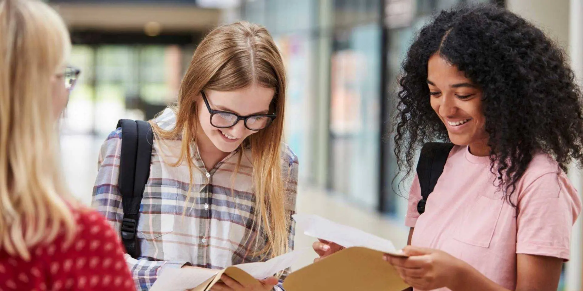 Three teenage girls reading their exam results - how can results day impact grieving young people