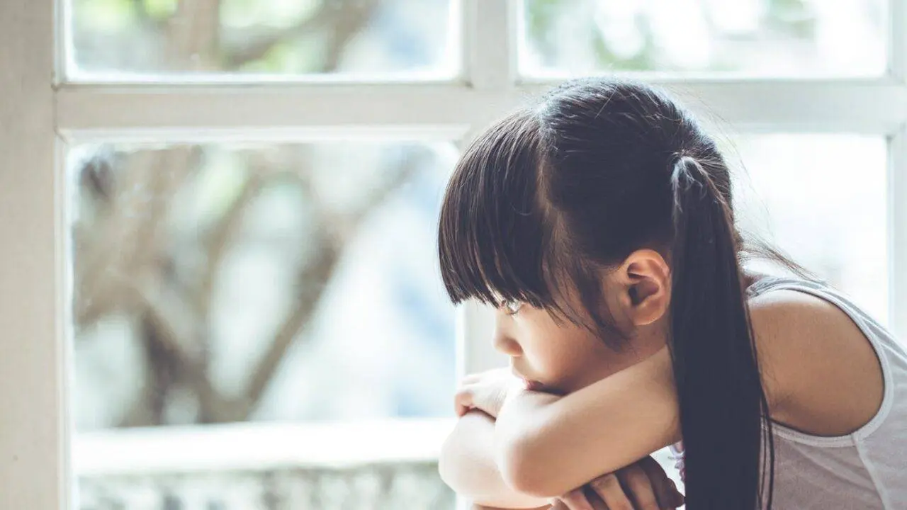 Photo of a young girl looking out of a window