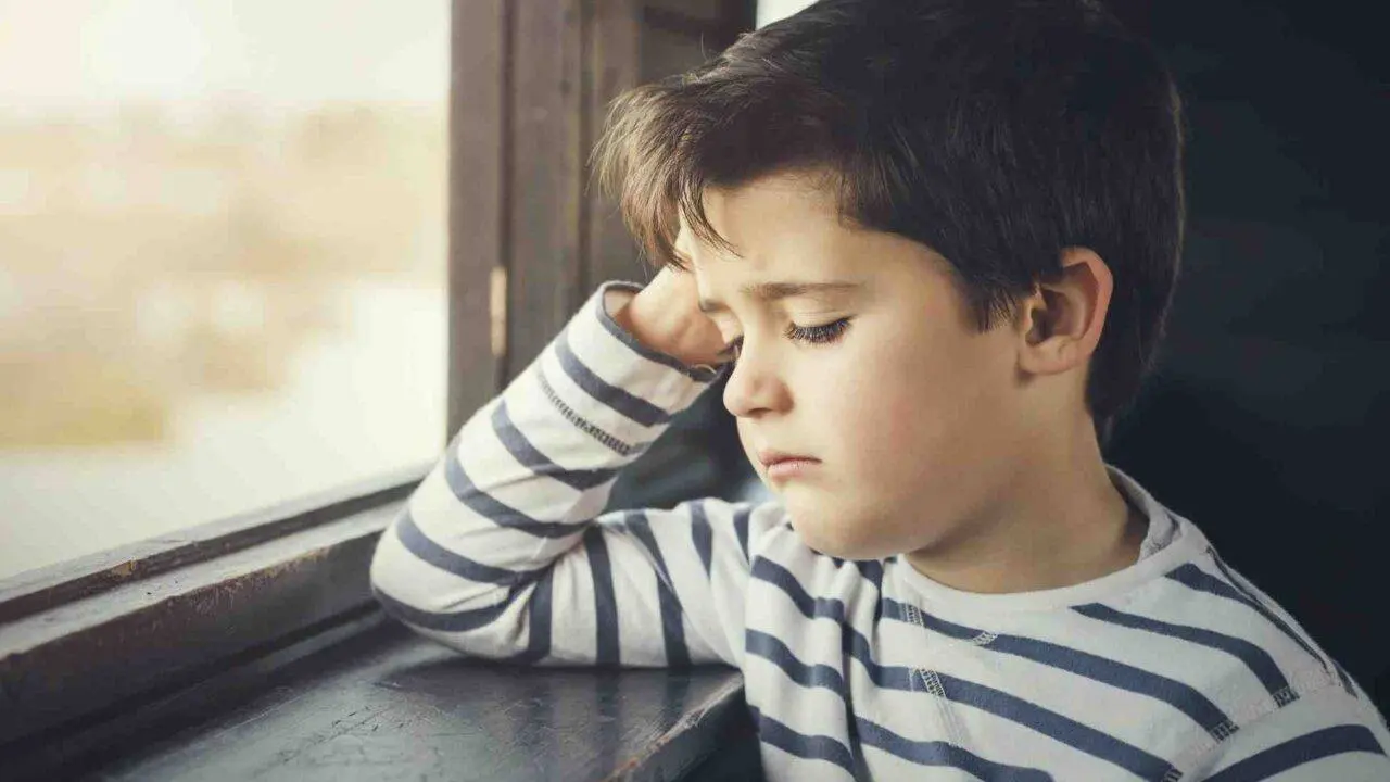 Young boy looking sadly out of the window