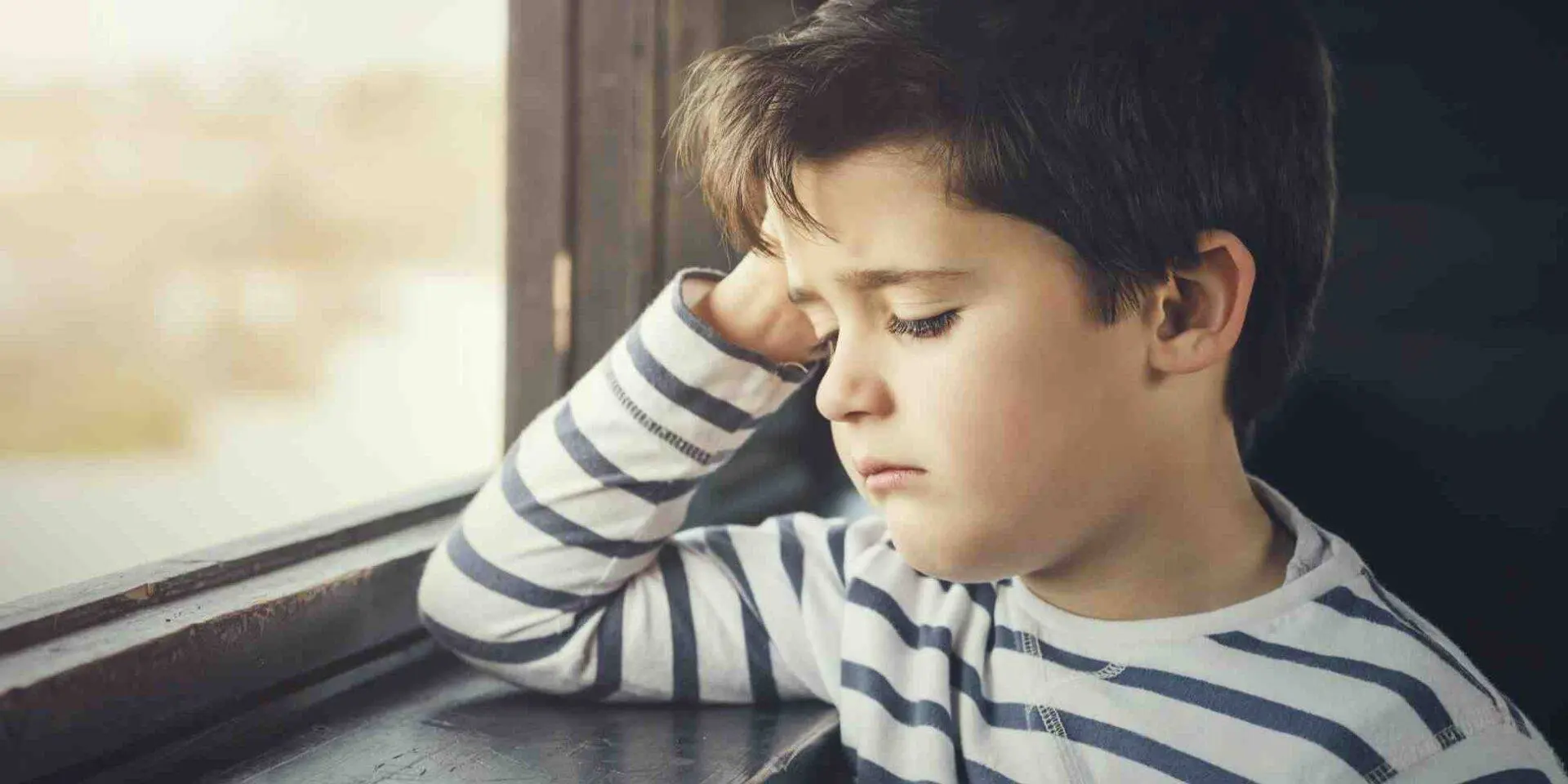 Young boy looking sadly out of the window