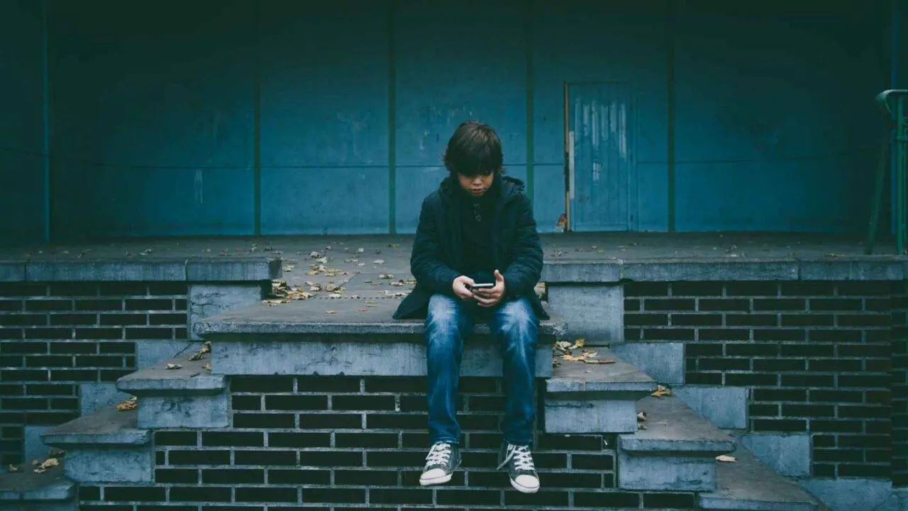 Photo of a teenage boy sat on a wall