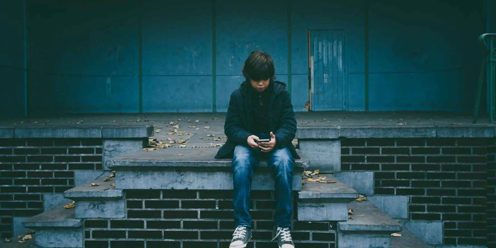 Photo of a teenage boy sat on a wall