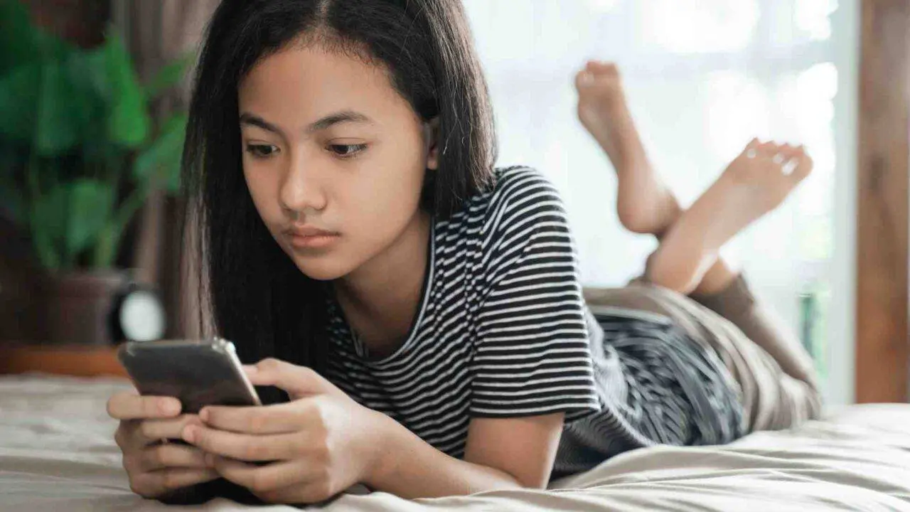 Teenage girl lying down and using a phone - Winston's Wish summer services