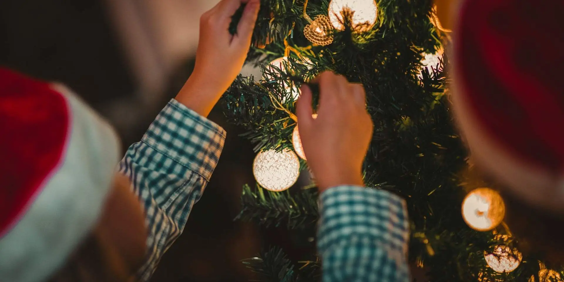 Child's hands decorating a Christmas tree