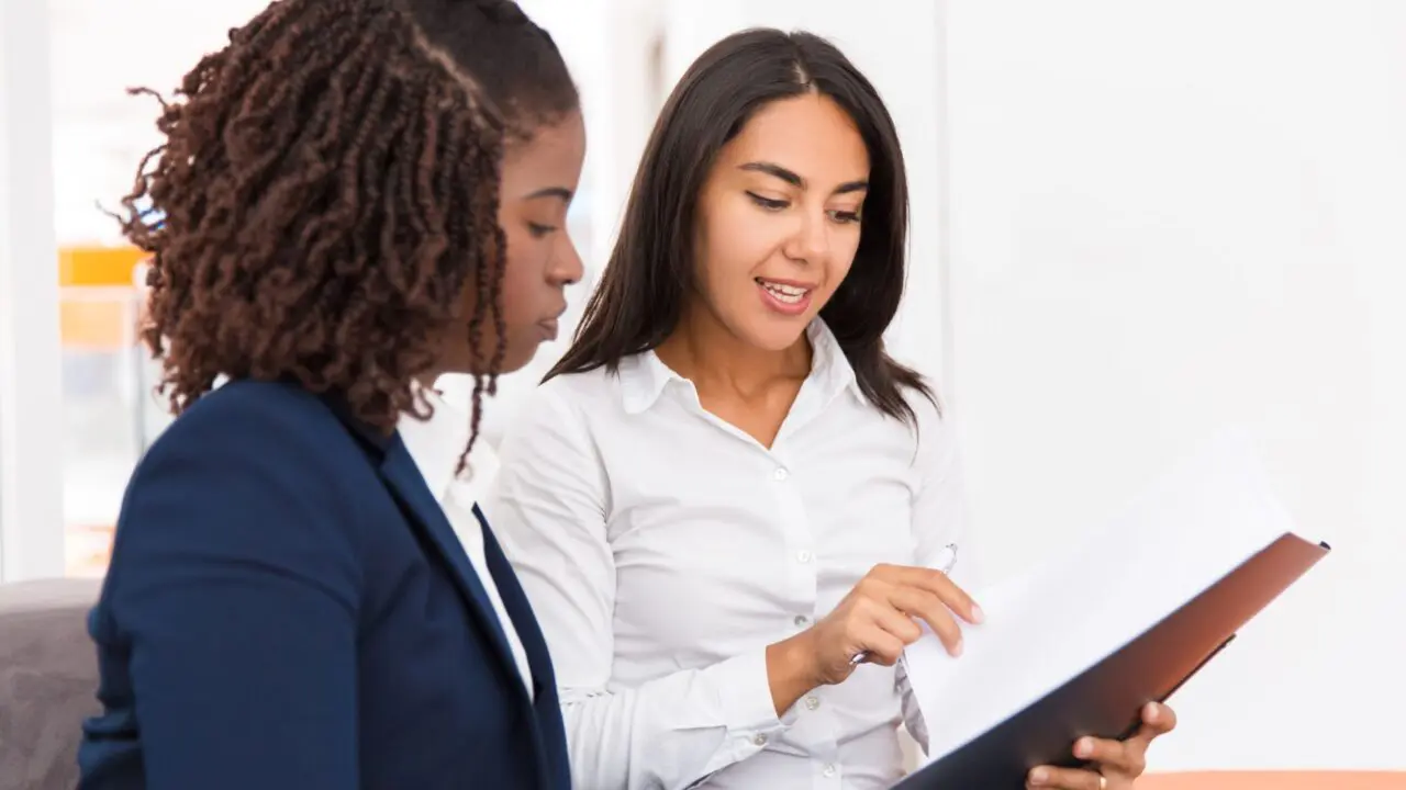 Two women sat side by side reviewing legal documents