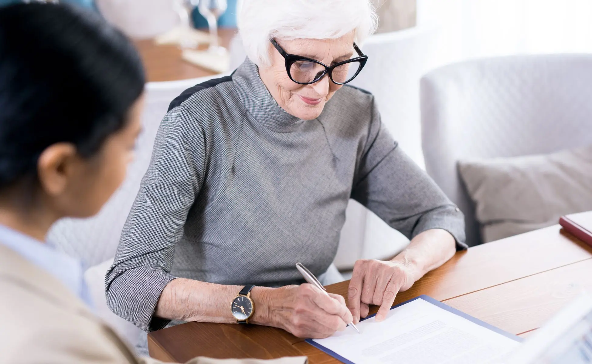 Woman sat with legal professional, signing a document