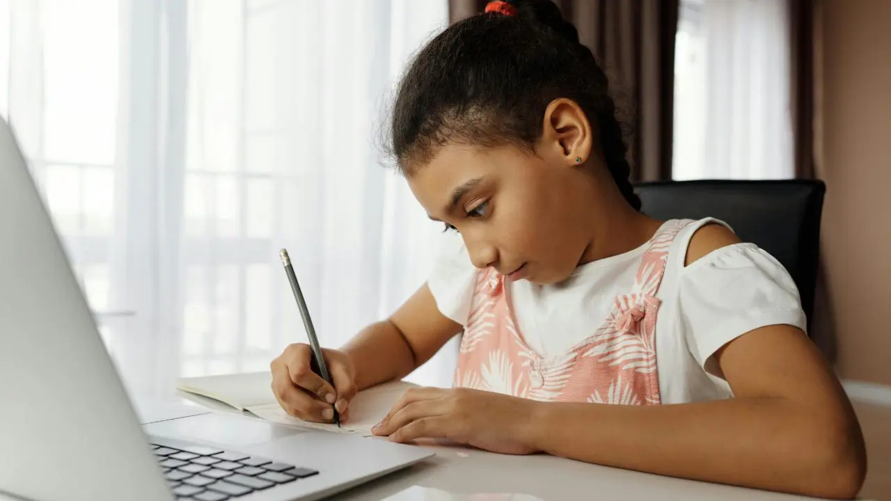 Small girl drawing in front of laptop