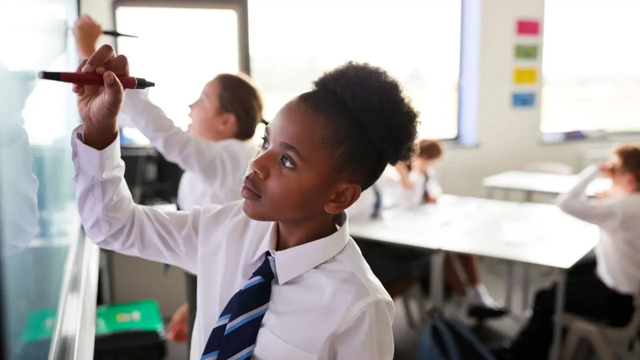 School girl drawing on a white board