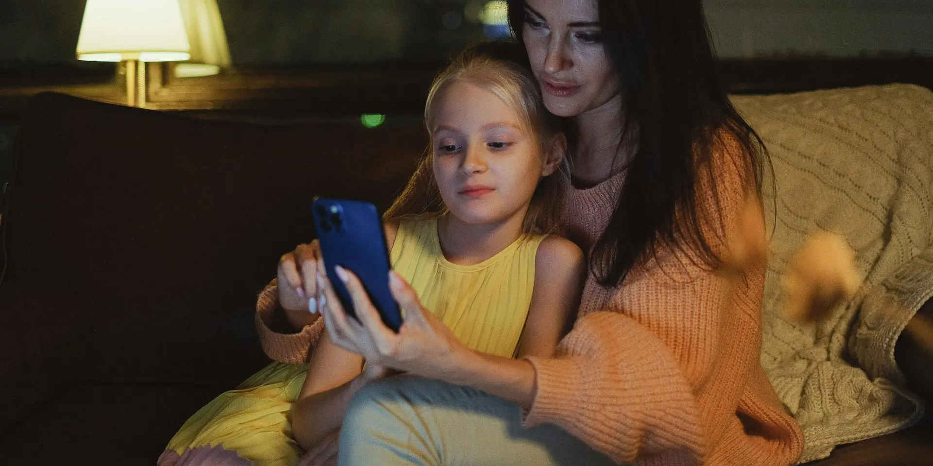 White mum using smartphone with daughter at home.