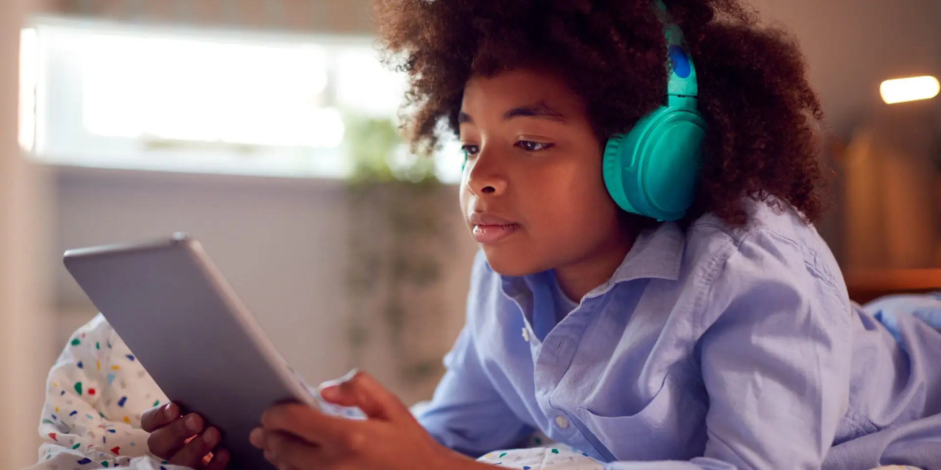 Black child wearing headphones looking at tablet device.