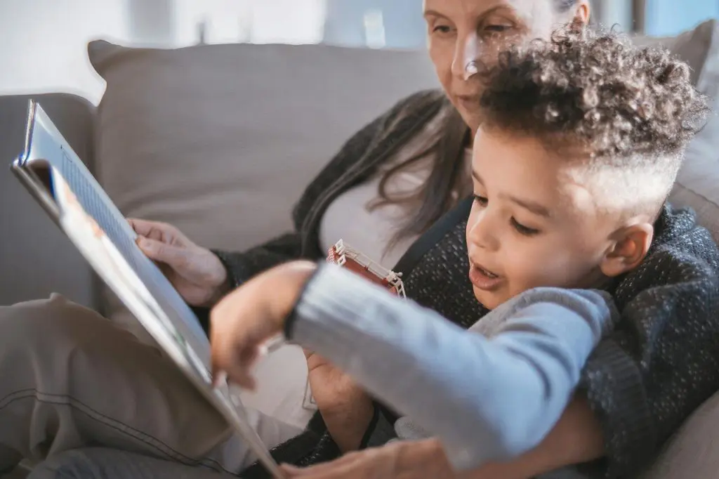 Young child reading a book with an adult