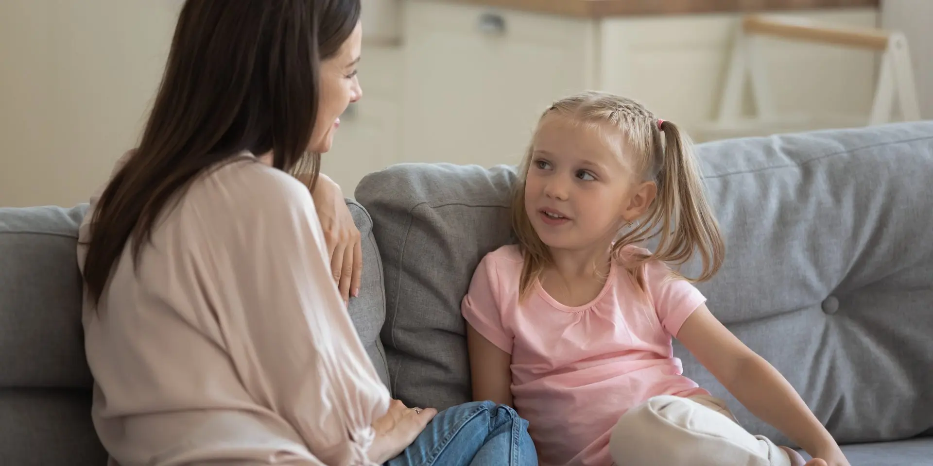 Adult and child having a conversation sitting on a sofa.