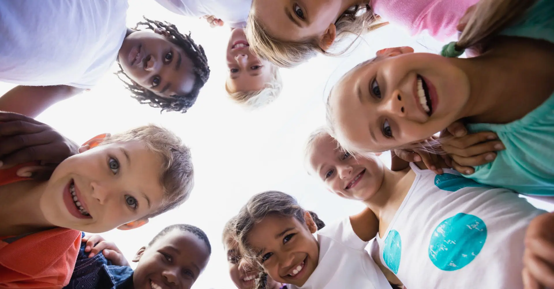 Young children in a circle looking down at the camera