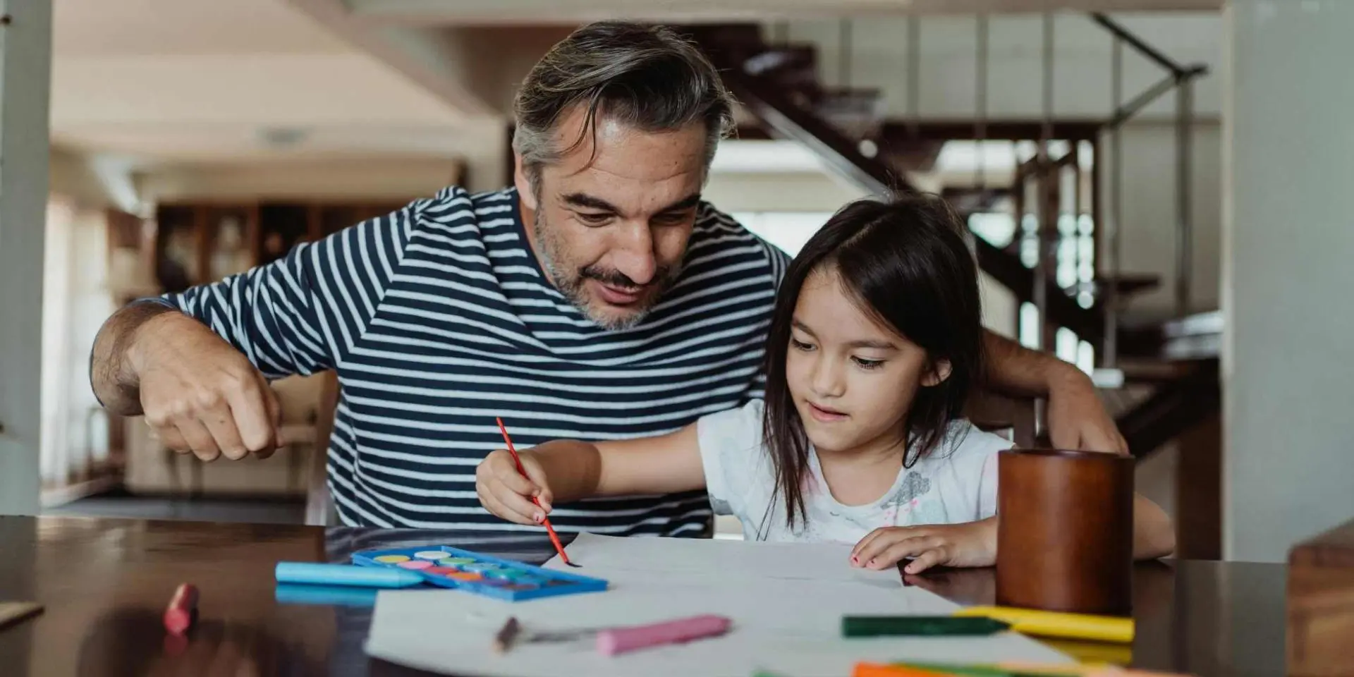 Dad and daughter sat at a table doing colouring - supporting neurodivergent grieving children