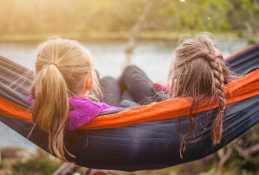 Two girls sitting on a hammock - manage grief over summer holidays - Photo by SI Janko Ferlic on Unsplash