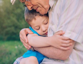 Young child hugging man.