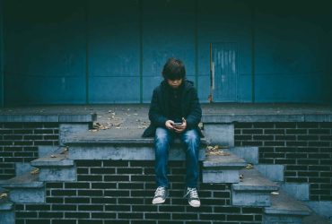 Photo of a teenage boy sat on a wall