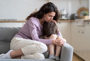 Woman comforting a small child on a sofa