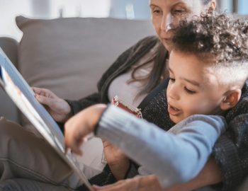 Young child reading a book with an adult
