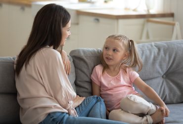 Adult and child having a conversation sitting on a sofa.